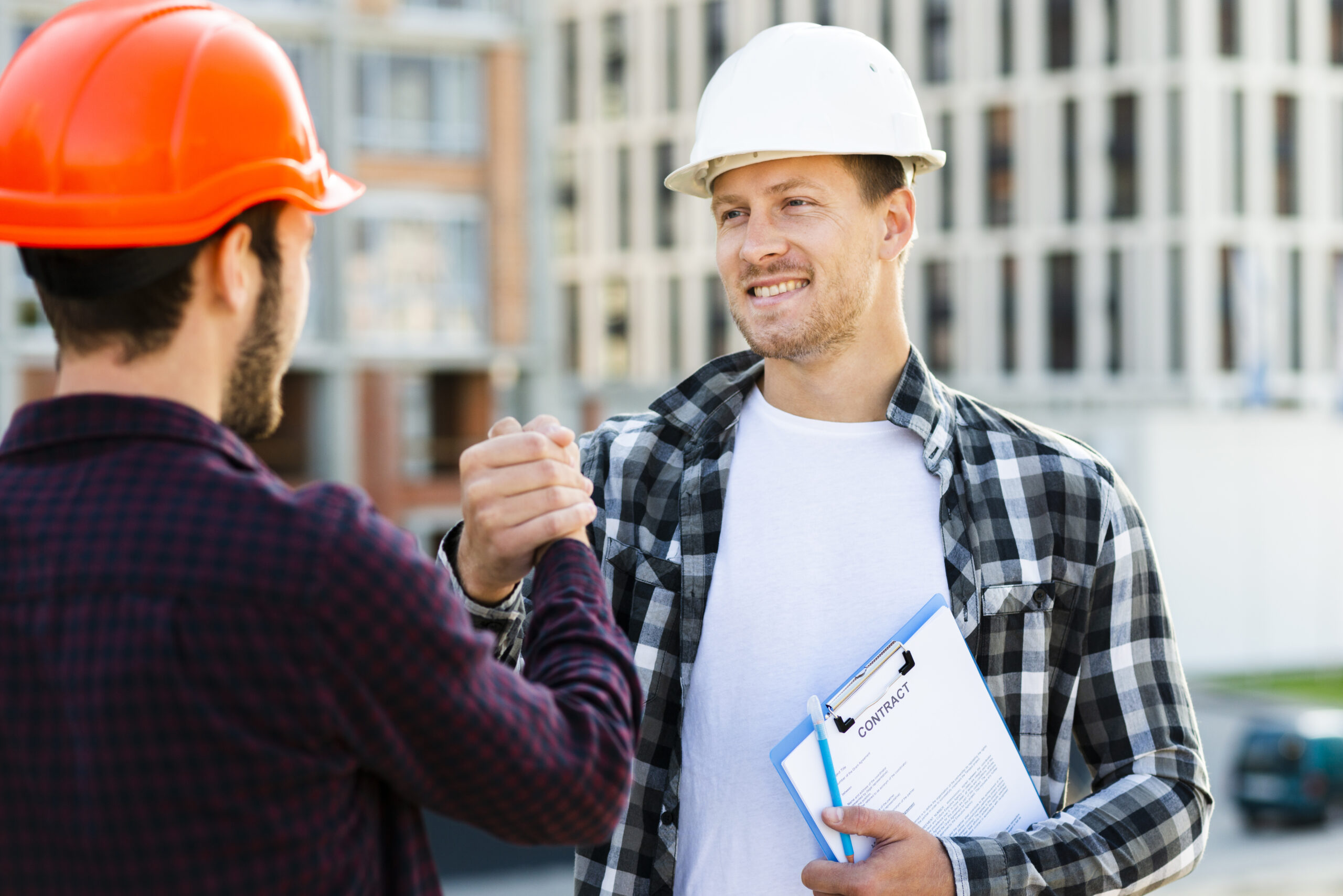 Two construction workers shake hands, symbolizing a collaboration agreement, with a contract in hand, emphasizing General Contractors and partnership in construction.